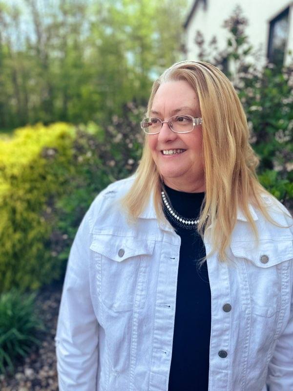 Sherry Clausen standing outside with verdant green backdrop